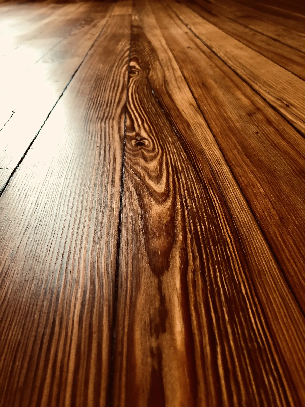 Low-angle close-up of finished antique heart pine flooring with dramatic cathedral grain