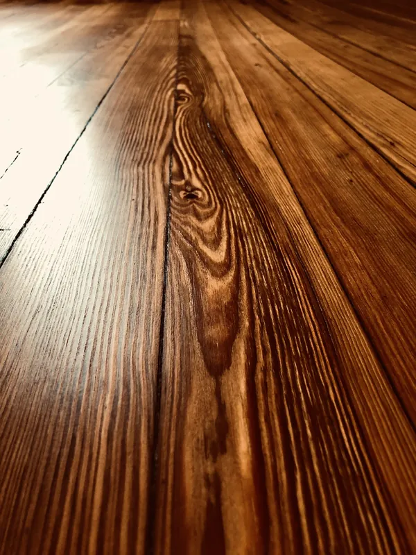 Low-angle close-up of finished antique heart pine flooring with dramatic cathedral grain and warm amber tone