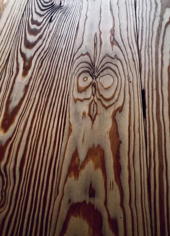 Close-up of wide heart pine floorboards showing swirling grain, resin streaks and a bold knot figure