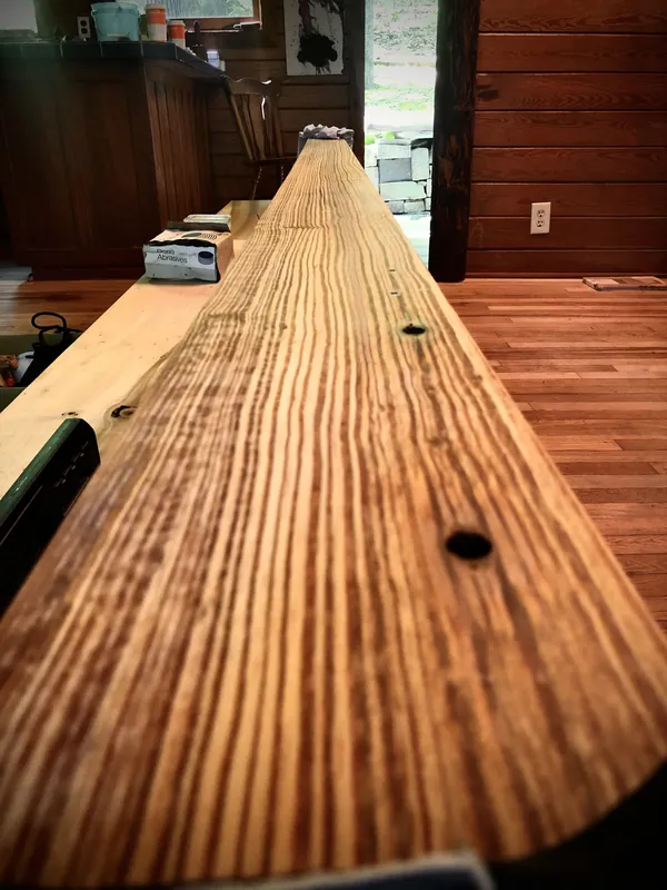 Long amber heart pine board with tight vertical grain running toward a bright doorway
