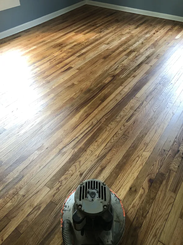 Floor buffer machine on a freshly stained warm-toned red oak strip floor