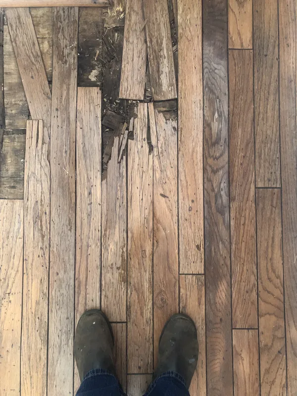 Damaged old oak floorboards, splintered and broken, flagged during assessment
