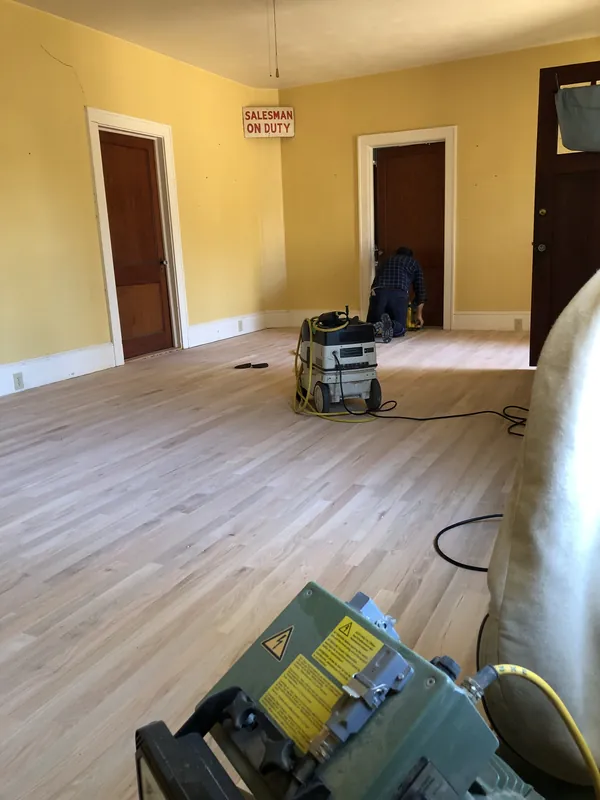 Floor sander on freshly laid light oak flooring in a commercial space
